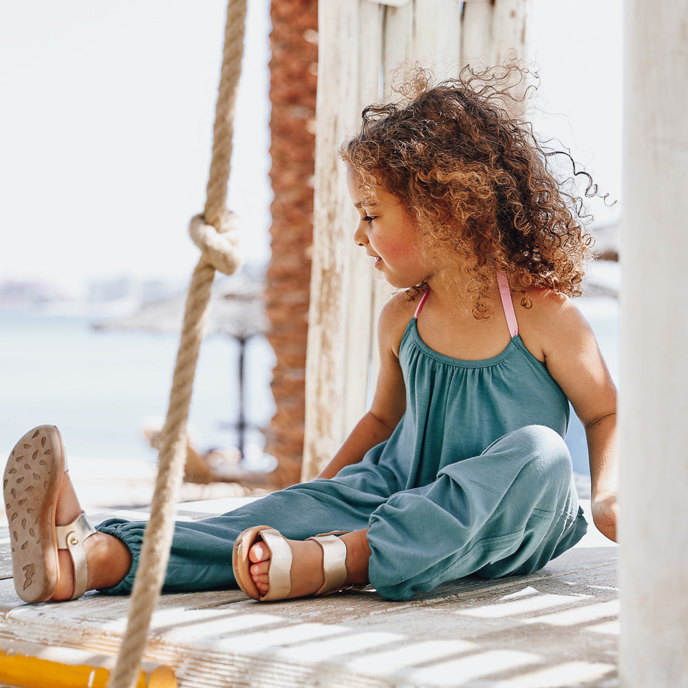 A girl walking wearing a Jade Green Halter Neck Romper by Hiccups & Buttercups