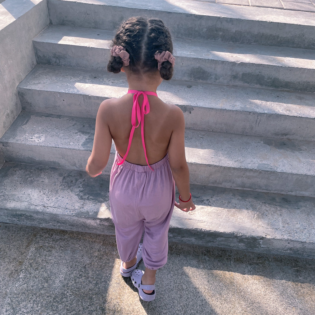 A girl walking up the stars wearing a Pastel Pink Halter Neck Romper by Hiccups & Buttercups