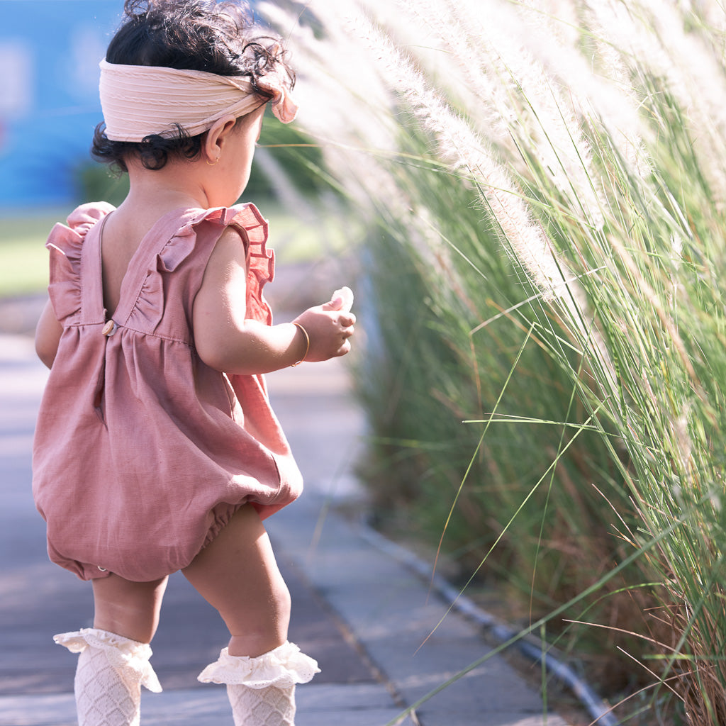 toddler wearing light pink classic linen Hiccups and Buttercups Romper