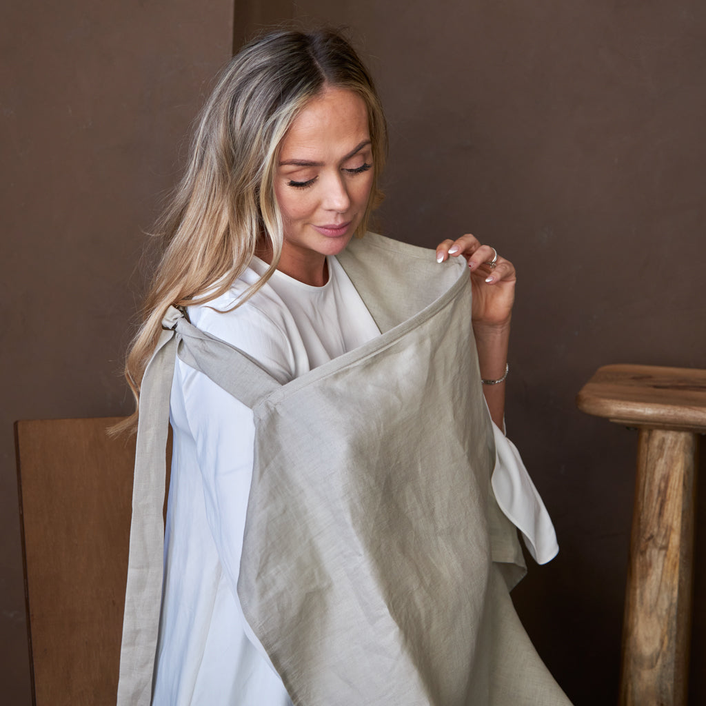 A mother nursing her baby using a Hiccups and Buttercups nursing cover