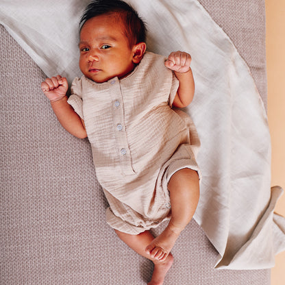 A beige short-sleeve cotton baby romper by Hiccups & Buttercups