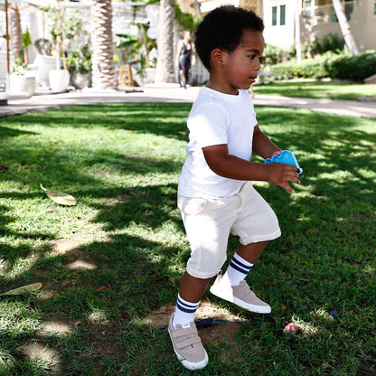 A boy wearing cream cotton shorts by Hiccups & Buttercups