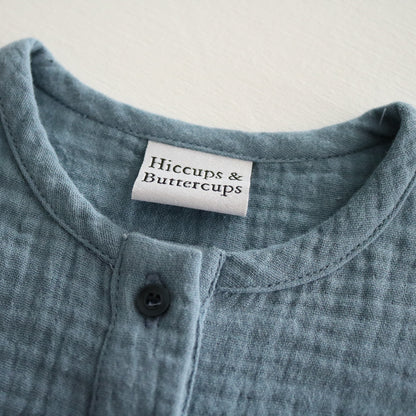 A blue short-sleeve cotton baby romper by Hiccups & Buttercups